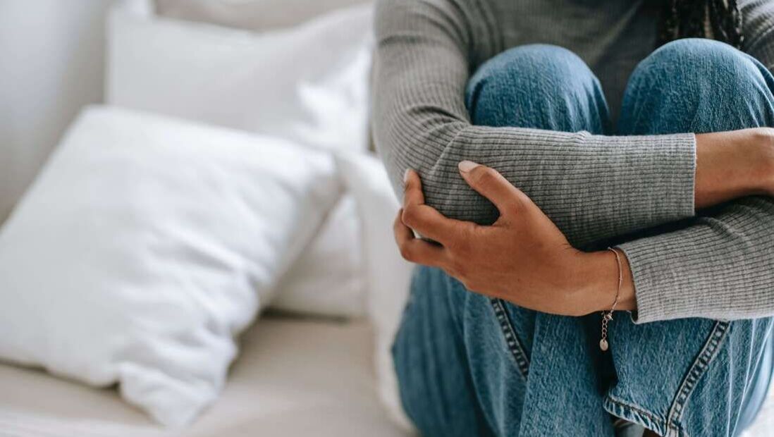 Photo of woman sitting on bed with arms wrapped around her. Seasonal depression can affect your mood, energy, and relationships. 